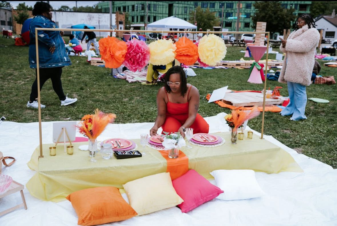 Vibrant outdoor picnic setup with colorful pillows and paper flowers