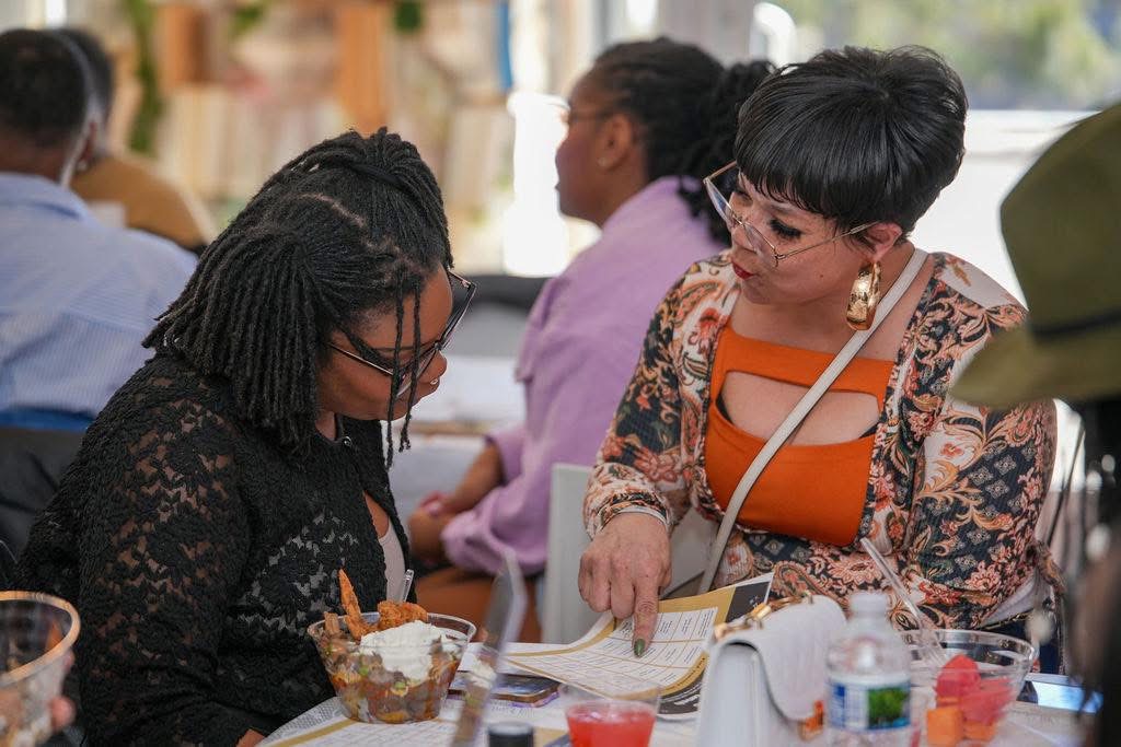 Two attendees collaborating over materials at an event table