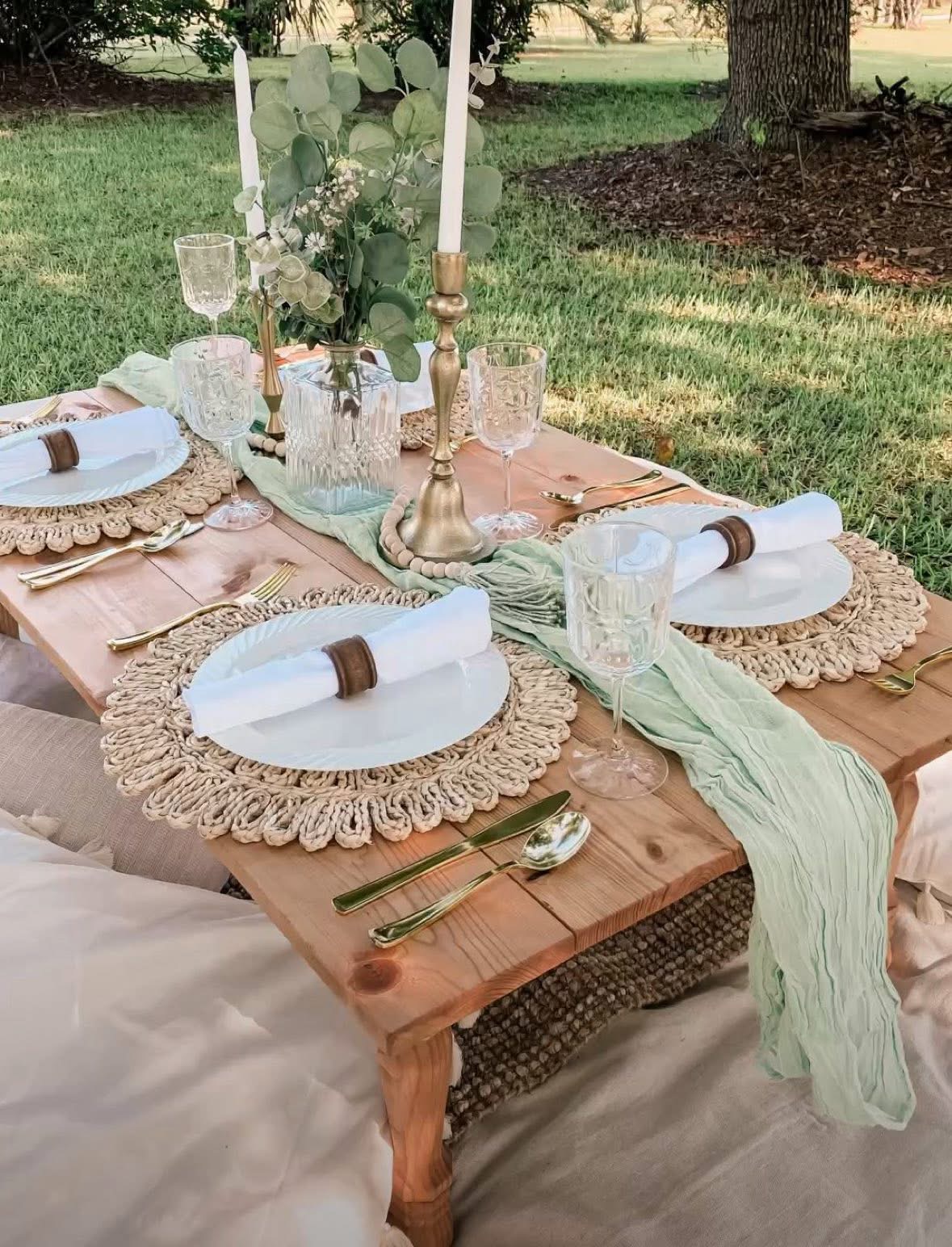 Elegant low tablescape with greenery, candles, and gold accents